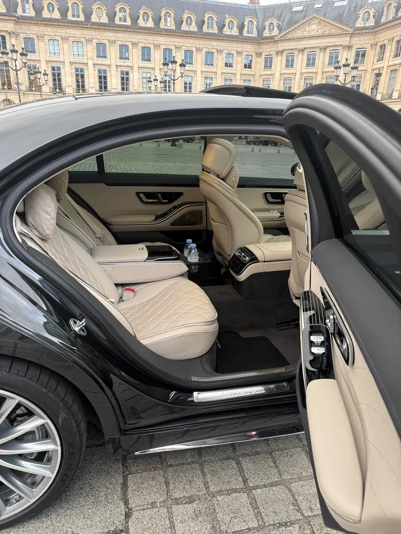 Rear door of a black Mercedes S-Class open onto an ivory leather cabin, Place Vendôme behind