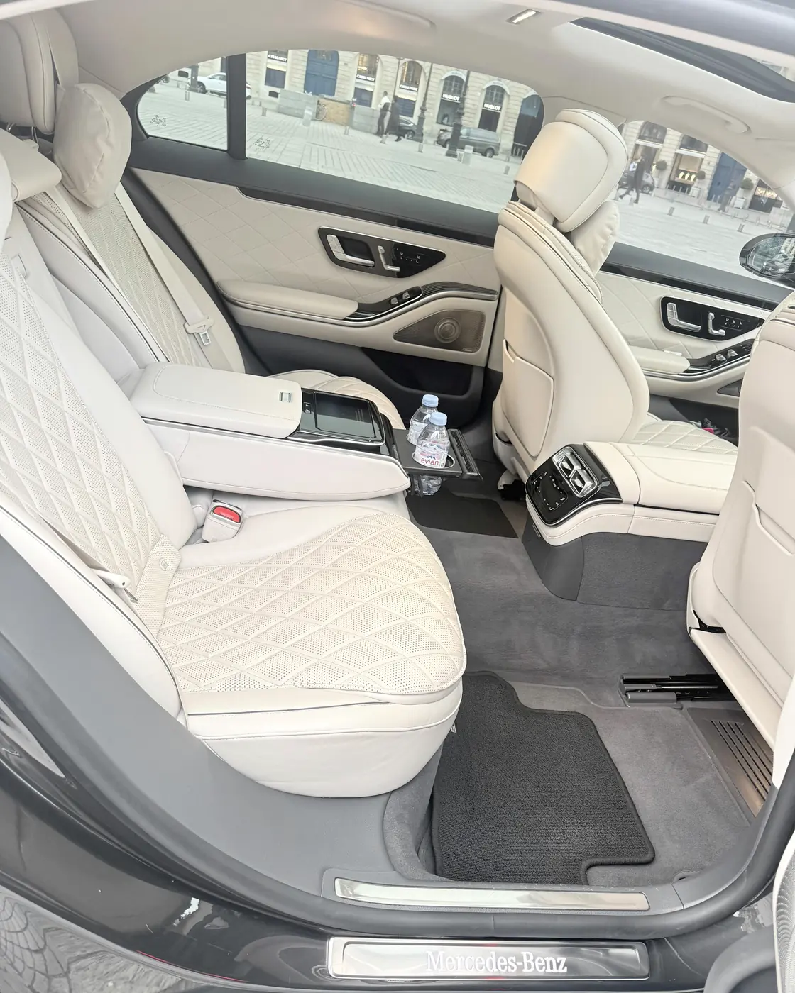 Habitacle arrière ivoire d’une Mercedes Classe S vu par la portière ouverte, la place Vendôme dans les vitres
